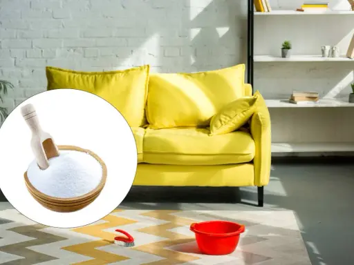 Un divano giallo brillante pronto per essere pulito con bicarbonato. Una ciotola di bicarbonato con un mestolo è in primo piano.