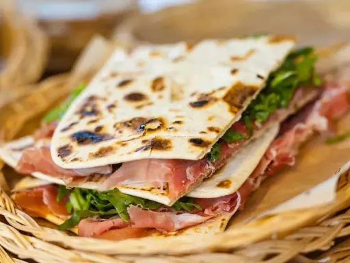Piadina romagnola con prosciutto crudo e rucola, un'ottima opzione per chi cerca dove mangiare a Rimini.