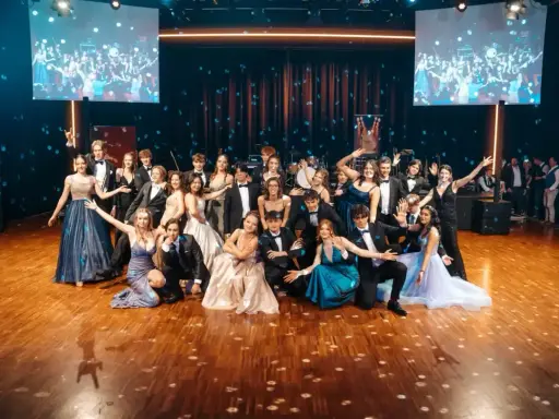 Junge Leute in festlicher Kleidung posieren für ein Gruppenfoto. Der **Ablauf** des **Abiballs** ist mit Tanz und guter Laune garantiert.
