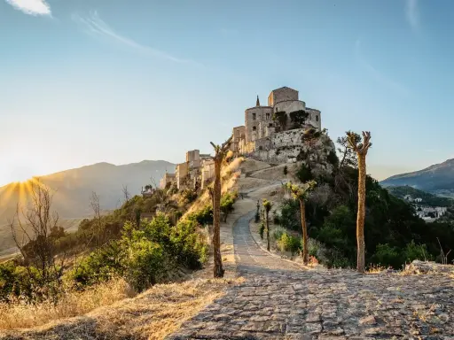 Petralia Soprana: cosa vedere in questo borgo arroccato, con un sentiero in pietra che sale verso il castello al tramonto.