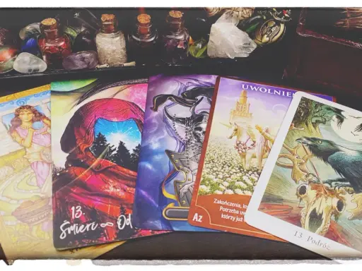 Tarot karta śmierci, numer 13, symbolizuje koniec i nowy początek. Obok niej inne karty i magiczne przedmioty.