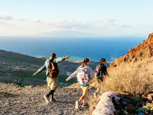 Vandrare njuter av utsikten över havet och landskapet på Santorini. En man pekar ut mot horisonten.