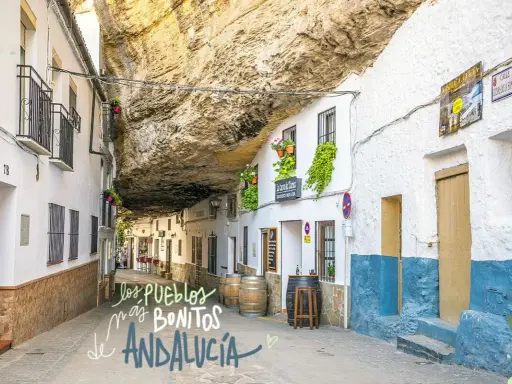 Calle bajo roca en Setenil de las Bodegas, uno de los pueblos mas bonitos de Andalucia. Casas blancas con balcones floridos y barriles de vino.