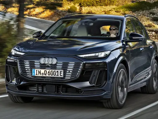 Ciemnogranatowy Audi Q6 e-tron jedzie po krętej drodze. Sprawdź atrakcyjną audi q6 e-tron cenę.