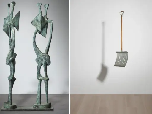 Two abstract bronze figures stand side-by-side, a modern sculpture. To the right, a metal snow shovel hangs suspended, its shadow cast on the wall.
