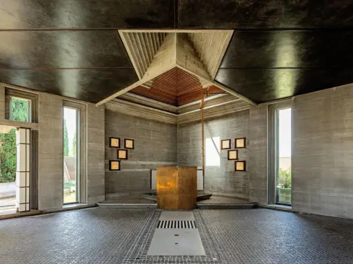 Interno moderno con altare dorato, pareti in cemento grezzo e soffitto a punta. Un esempio di architetti famosi italiani.