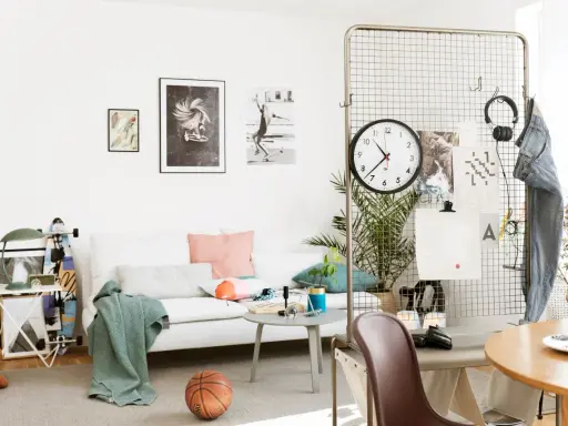 Här är en inspirerande etta på 25 kvm med en vit soffa, konst på väggarna, en basketboll och en grön pläd.