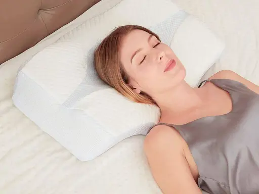Mujer durmiendo plácidamente sobre una almohada ergonómica. Aprende como colocar la almohada correctamente para un descanso óptimo.