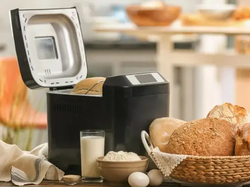Machine à pain ouverte, avec du pain frais dans un panier. Avis sur la machine à pain : facile et pratique pour un pain maison.