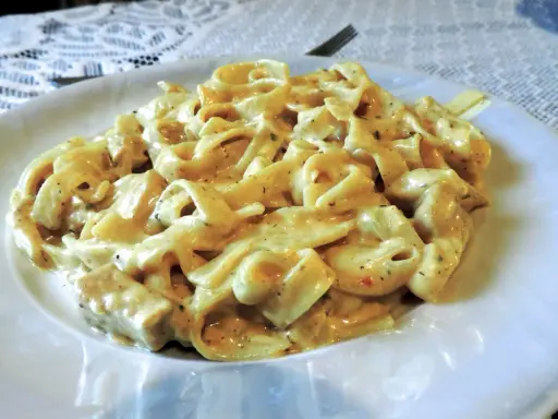 Pyszne tagliatelle z kurczakiem w kremowym sosie, podane na białym talerzu.