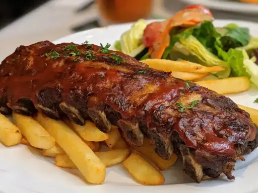 Soczyste żeberka w sosie BBQ, podane z chrupiącymi frytkami i świeżą sałatką. Idealna marynata do żeberek sprawia, że mięso jest niezwykle aromatyczne.
