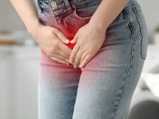 Kobieta trzyma się za podbrzusze, odczuwając ból brzucha przy zapaleniu pęcherza.