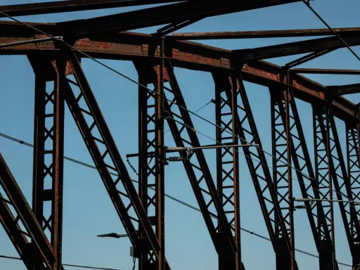 Estructura de puentes de hierro famosos contra el cielo azul. Cables cruzan la intrincada red de vigas oxidadas.