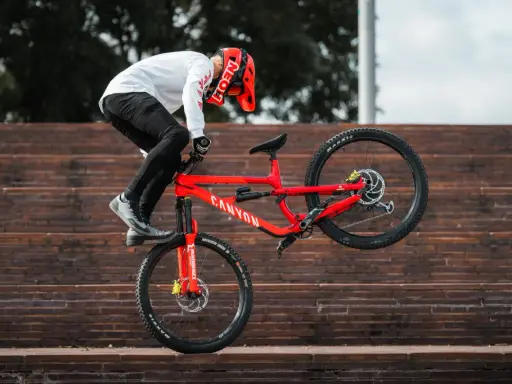 Gabriel Wibmer balanciert auf seinem roten Canyon Bike auf einer Treppe.