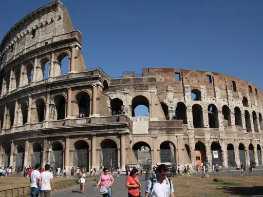 Le Colisée de Rome avant sa restauration complète, avec des touristes admirant son architecture antique sous un ciel bleu.