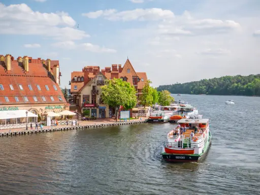 Port w Mikołajkach z zacumowanymi statkami i kamieniczkami. Wspaniałe mikołajki atrakcje dla turystów.