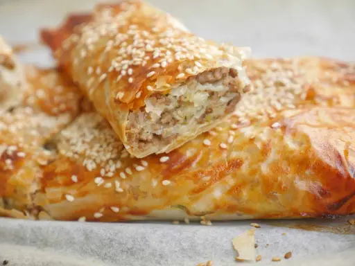 Krispig filodegsrulle fylld med köttfärs och lök, toppad med sesamfrön. Ett perfekt filodeg recept för en god måltid.