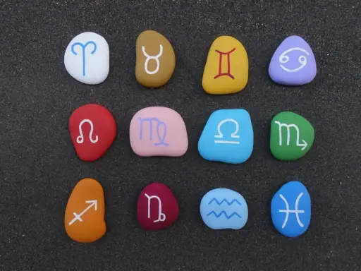 Kolorowe kamienie z symbolami zodiaku ułożone w rzędach. Sprawdź dopasowanie znaków zodiaku!
