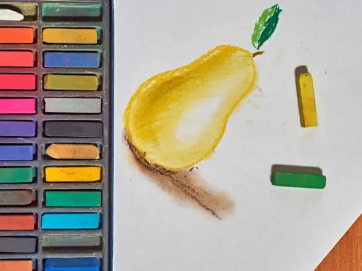 Boîte de pastels secs et une poire dessinée. Apprenez comment faire des pastel en utilisant ces couleurs vives.