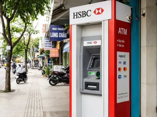 Bankomat HSBC w Hanoi, gotowy do wypłaty waluty. W tle widać ruchliwą ulicę z motocyklami i sklepami.