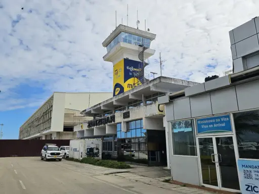 Kontrolltorn och terminalbyggnad vid Zanzibar flygplats. En vit SUV parkerad framför.