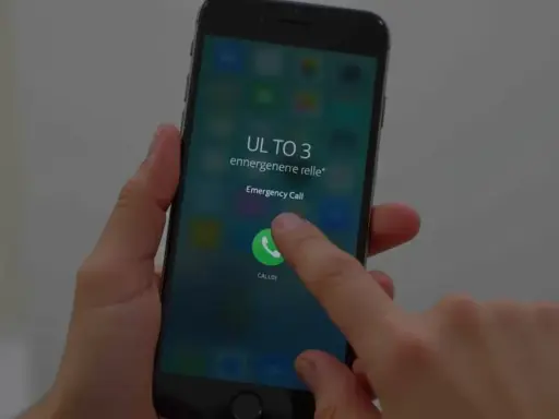 Dłoń naciska przycisk "Emergency Call" na ekranie telefonu, pokazując, jak odblokować telefon przez połączenie alarmowe.