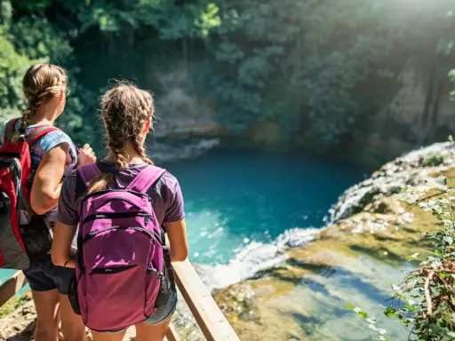 Due escursioniste con zaini ammirano una cascata turchese durante il loro trekking in Toscana.