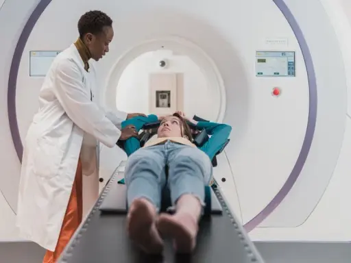 Lekarz przygotowuje pacjentkę do badania tomografem komputerowym.