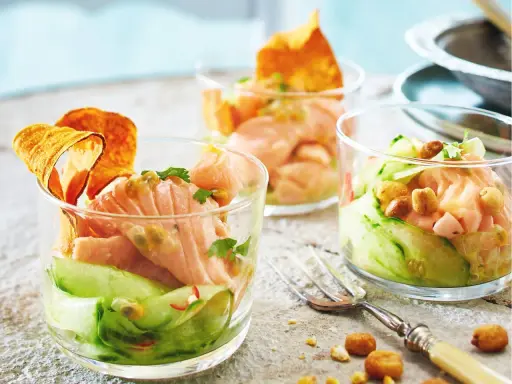 Drei Gläser mit raffinierten Vorspeisen zum Vorbereiten: Lachs-Tatar mit Gurke, Passionsfrucht und knusprigen Chips.