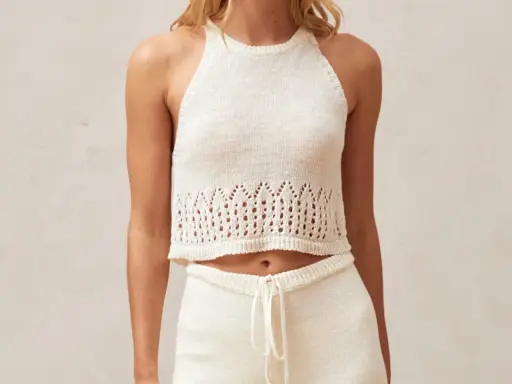 Top a ganchillo blanco con detalles calados en el bajo.