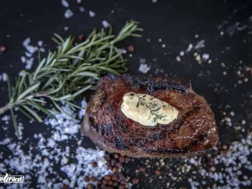 Perfekt medium gegrilltes Steak mit Kräuterbutter, Rosmarin und grobem Salz.