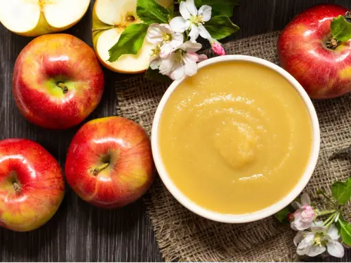 Frische Äpfel und eine Schüssel mit selbstgemachtem Apfelmus, garniert mit Apfelblüten. Ein Genuss für alle Sinne!