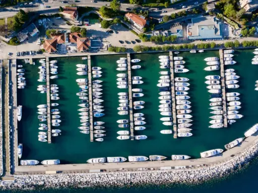 Widok z lotu ptaka na port w Chorwacji, pełen białych jachtów i łodzi zacumowanych w turkusowej wodzie.