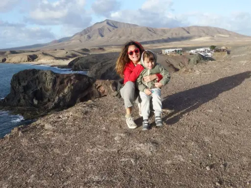 Mamma e bambino felici a Lanzarote con bambini, con vista sulle scogliere e montagne vulcaniche.
