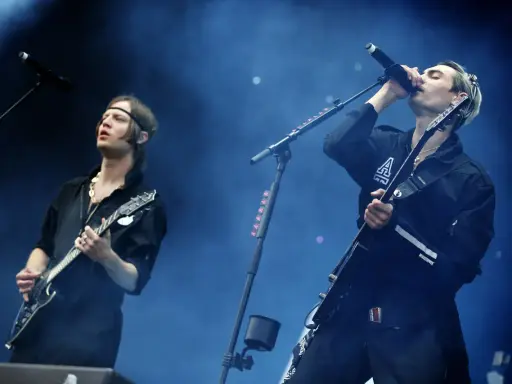 Gustaf Norén sjunger och spelar gitarr med Mando Diao på scenen, omgiven av rök och blått ljus.