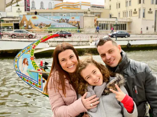 Familia feliz disfrutando de un paseo en góndola en Aveiro con niños. La niña hace el signo de la paz.