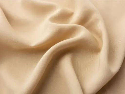 A close-up of draped beige viscose fabric. It feels smooth and cool, like silk, with a subtle sheen.