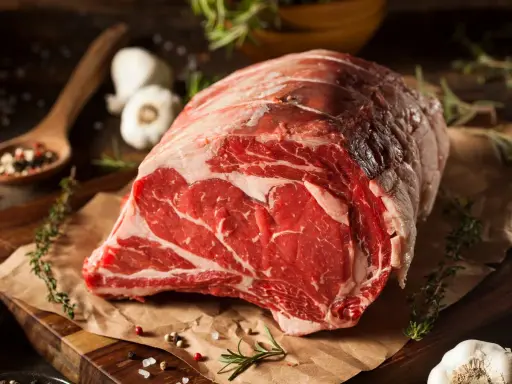 Un succulento pezzo di carne cruda, pronto per diventare un delizioso brasato di manzo. Spezie, erbe aromatiche e aglio completano la scena.