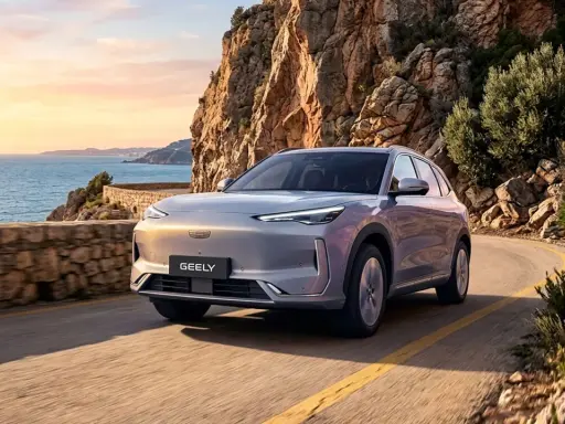 Un Geely plateado recorre una carretera costera en España al atardecer, con el mar Mediterráneo y acantilados rocosos de fondo.