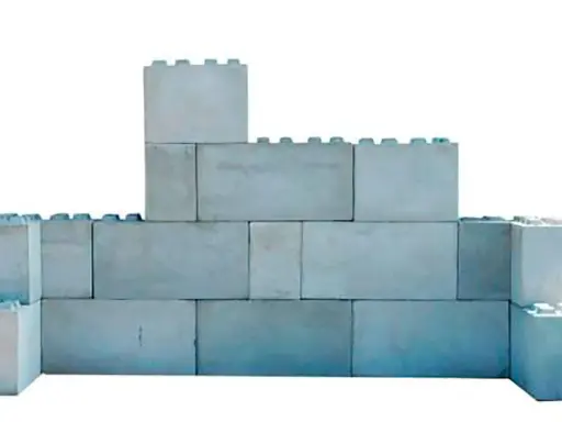 Una pared de bloques grises, apilados de forma irregular, simula un castillo de juguete.