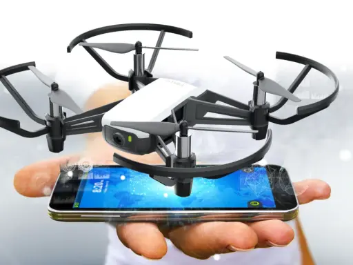 Kleine Drohne schwebt über einem Smartphone, das die tello app anzeigt.