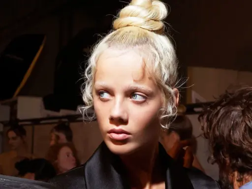 Ein Model mit einem eleganten Dutt und zarten Babyhaaren, die um das Gesicht fallen.