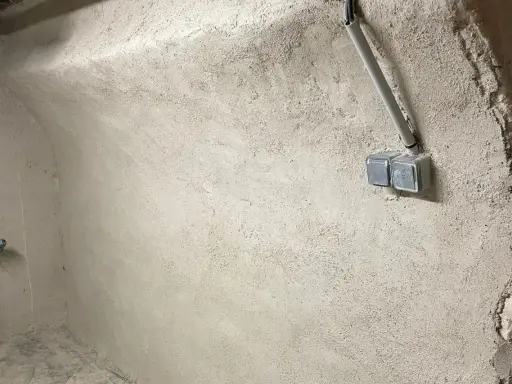 Murs bruts avec prises électriques et tuyauterie, étape clé pour savoir comment assainir une maison.