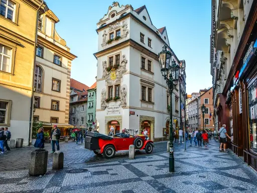 Uliczka w Pradze z czerwonym kabrioletem i zabytkowymi kamienicami. Złota uliczka Praga zachwyca.