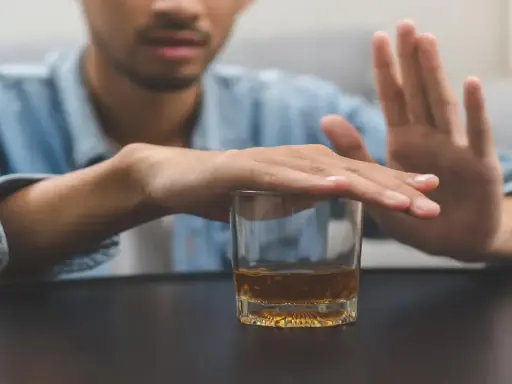 Mężczyzna odrzuca szklankę z alkoholem, symbolizując walkę z nałogiem. To obraz przymusowego leczenia alkoholika, który decyduje się na zmianę.