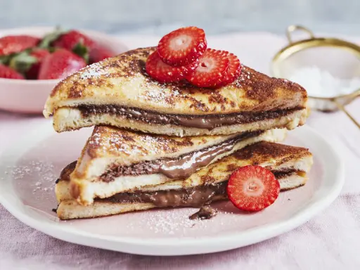 Gestapelte French Toast mit Nutella, bestäubt mit Puderzucker und garniert mit Erdbeeren. Ein süßer Genuss!