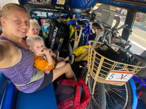 Familj i tuk-tuk med barn och cyklar, en del av en budgetresa i Thailand.