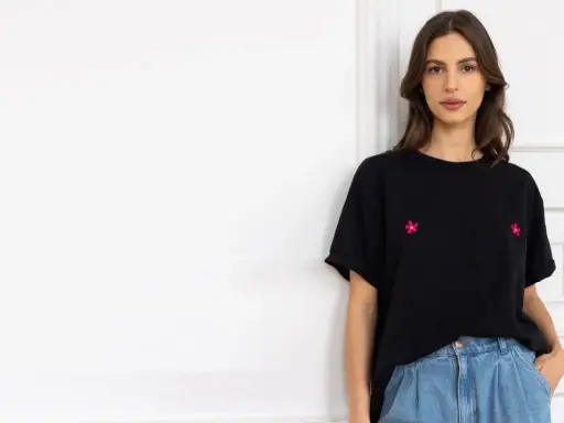 Kobieta w czarnym t-shircie z haftowanymi kwiatkami i jeansach. Stylowy sposób, jak nosić t-shirt w spodniach.