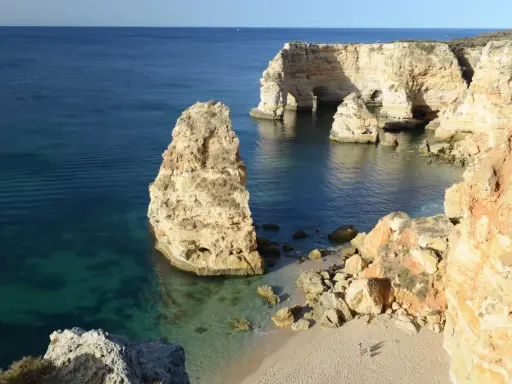 Felsformationen und eine kleine Bucht bei Ilha de Tavira. Das klare Wasser schimmert türkis.