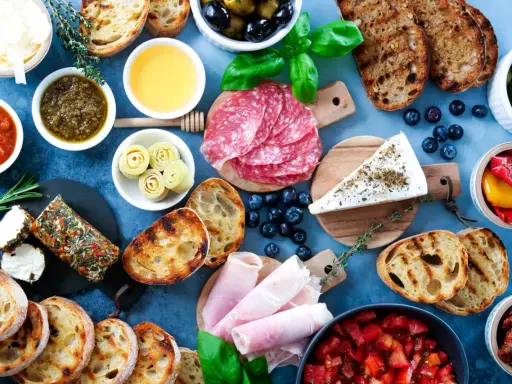 Eine köstliche italienische Vesperplatte mit Salami, Käse, Brot, Oliven und eingelegtem Gemüse.